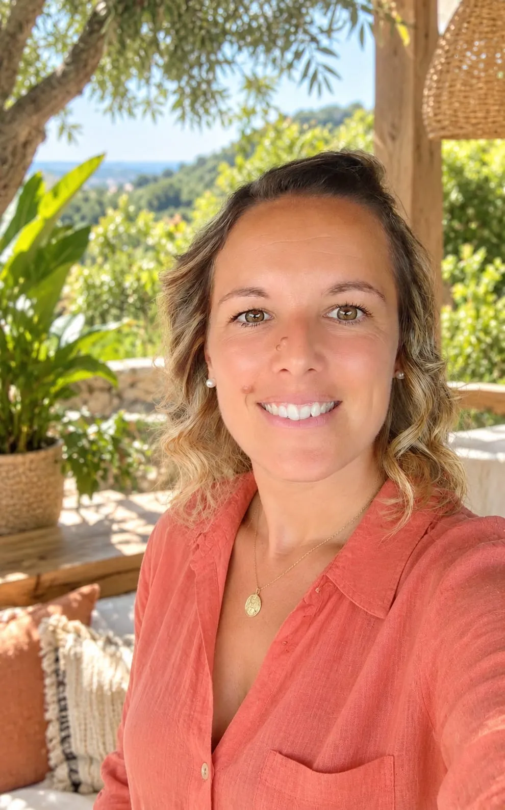 Nathalie Coudour, souriante, sur une terrasse ombragée face aux collines